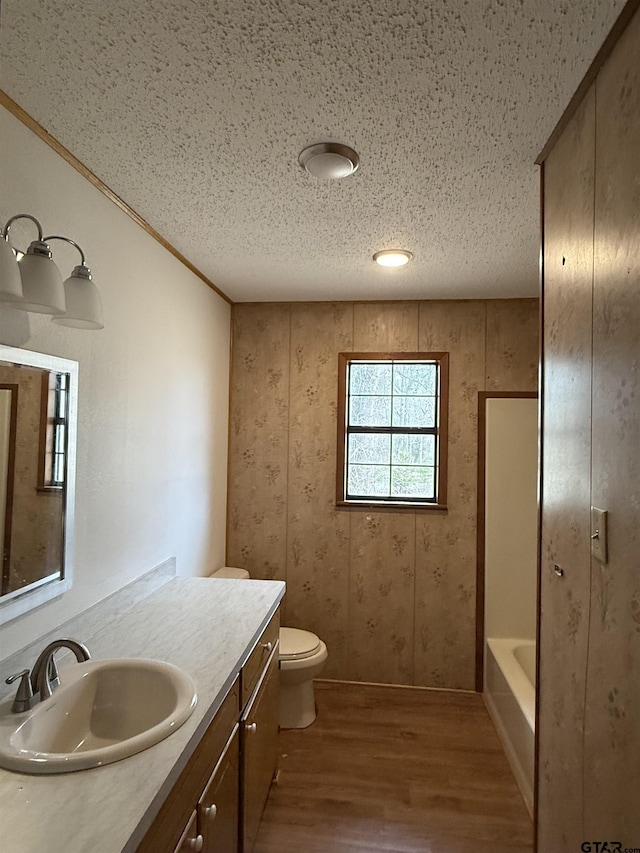 bathroom with vanity, toilet, hardwood / wood-style floors, and a textured ceiling