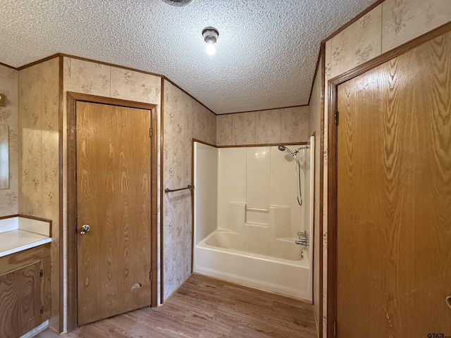 bathroom with washtub / shower combination, crown molding, a textured ceiling, vanity, and hardwood / wood-style floors