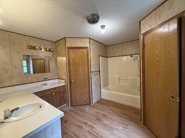 bathroom with wood-type flooring, vanity, a textured ceiling, and shower / tub combination