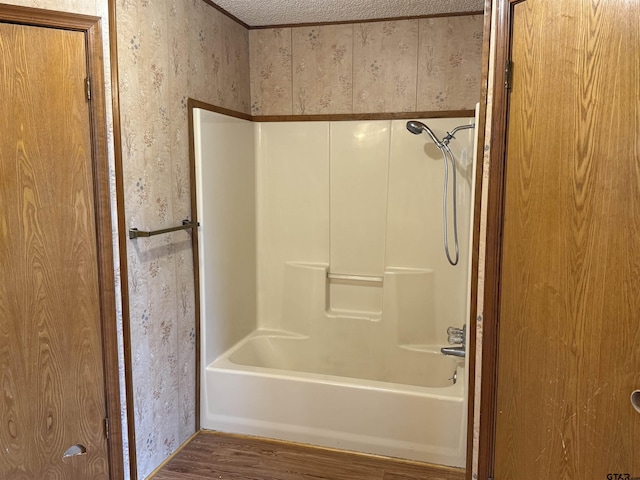 bathroom with shower / tub combination, hardwood / wood-style floors, and a textured ceiling