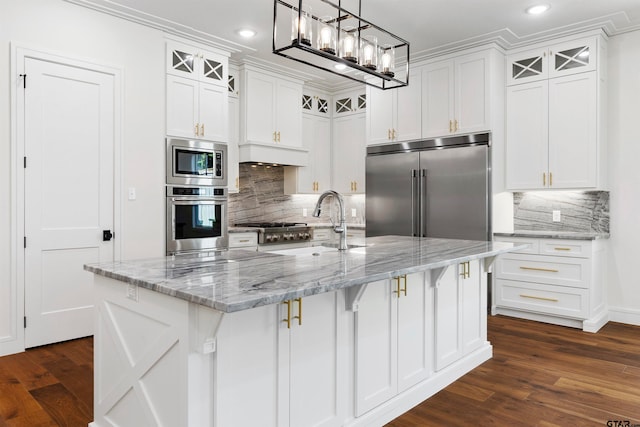 kitchen featuring built in appliances, dark hardwood / wood-style floors, white cabinetry, and a kitchen island with sink