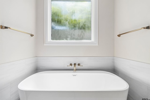 bathroom featuring a washtub and tile walls