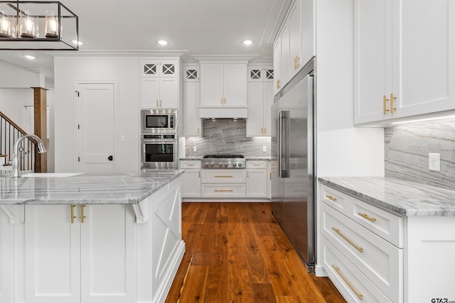 kitchen featuring sink, dark hardwood / wood-style floors, appliances with stainless steel finishes, light stone counters, and white cabinetry