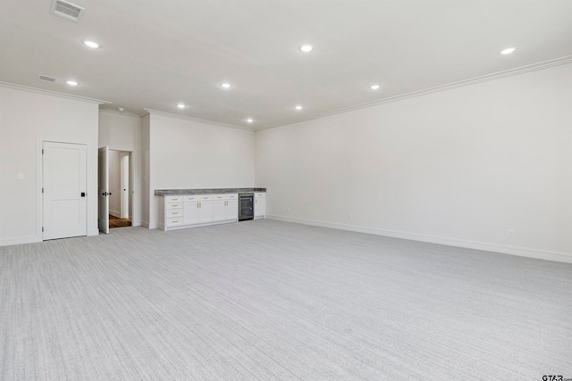 spare room with beverage cooler, light colored carpet, and ornamental molding