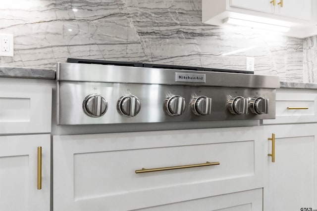 room details with backsplash, stainless steel cooktop, and white cabinets