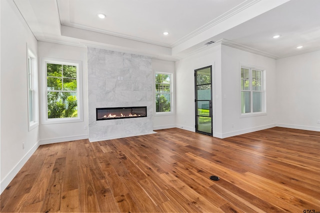 unfurnished living room with wood-type flooring, ornamental molding, and a tile fireplace