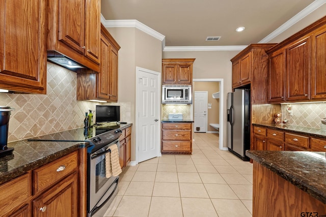 kitchen featuring ornamental molding, light tile patterned flooring, backsplash, appliances with stainless steel finishes, and dark stone countertops