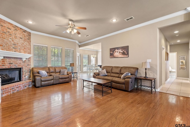 living room featuring a fireplace, ceiling fan, light hardwood / wood-style flooring, and ornamental molding