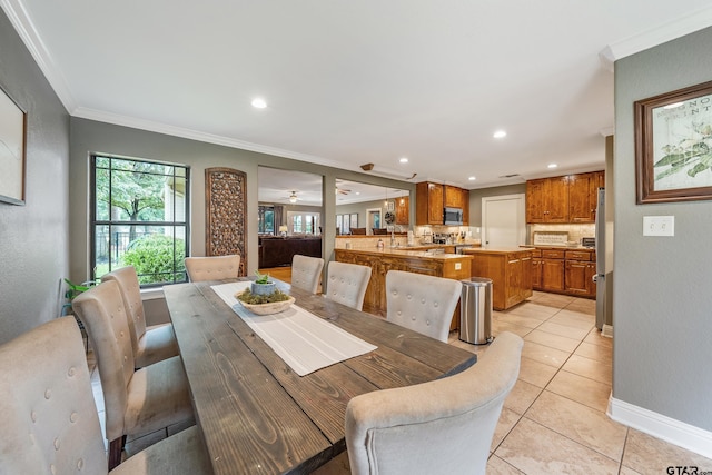 tiled dining room with ornamental molding and ceiling fan