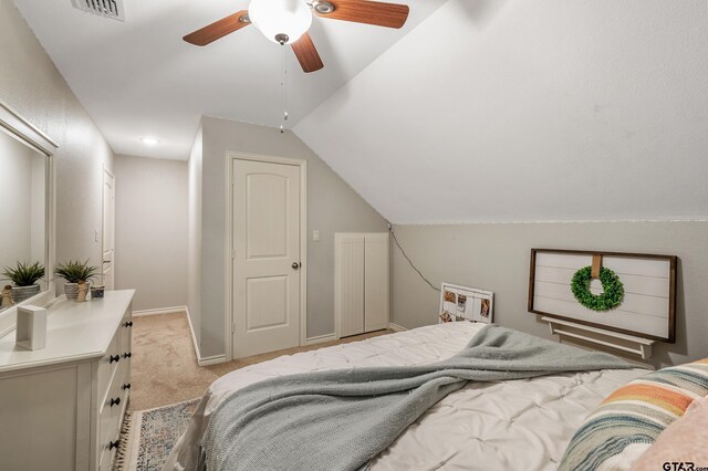 bedroom with ceiling fan, light colored carpet, and vaulted ceiling