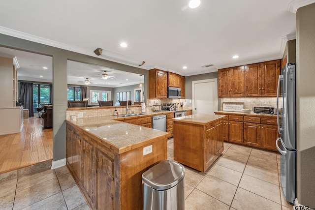 kitchen with stainless steel appliances, light tile patterned floors, sink, kitchen peninsula, and a center island