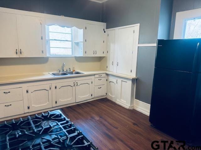 kitchen with black refrigerator, dark hardwood / wood-style floors, sink, and white cabinetry