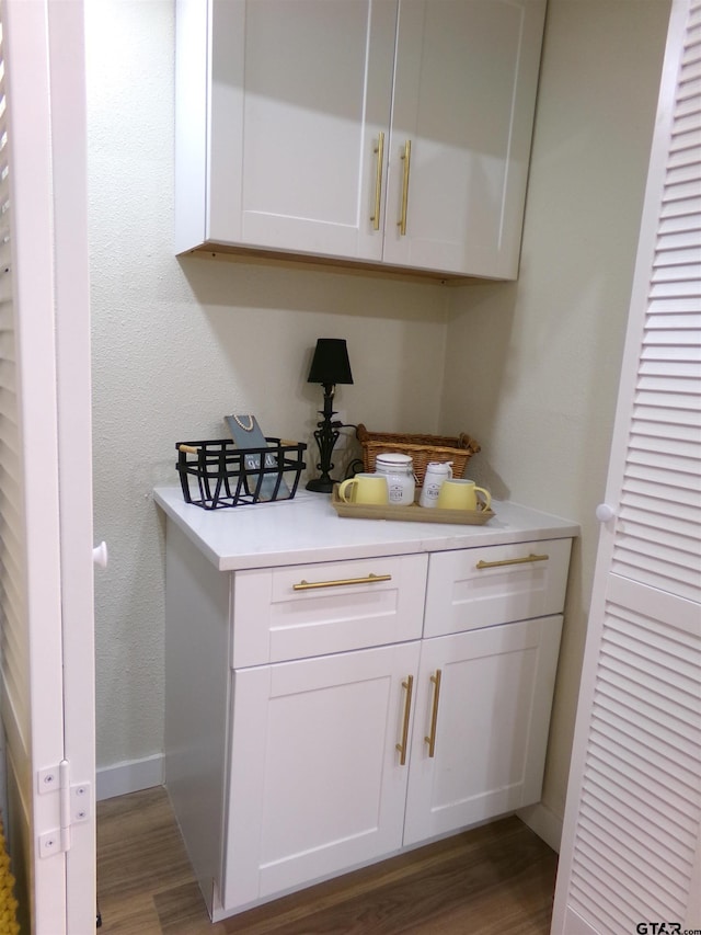 bar with white cabinets and dark wood-type flooring