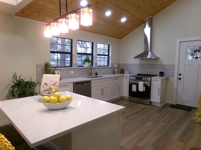 kitchen with appliances with stainless steel finishes, dark wood-type flooring, wall chimney range hood, decorative light fixtures, and white cabinets