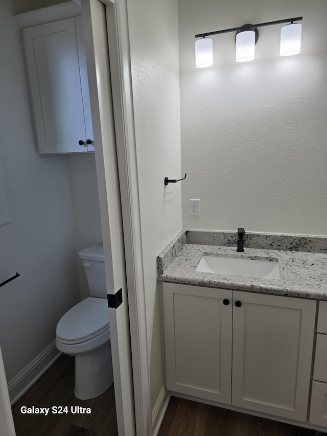 bathroom with toilet, baseboards, wood finished floors, and vanity