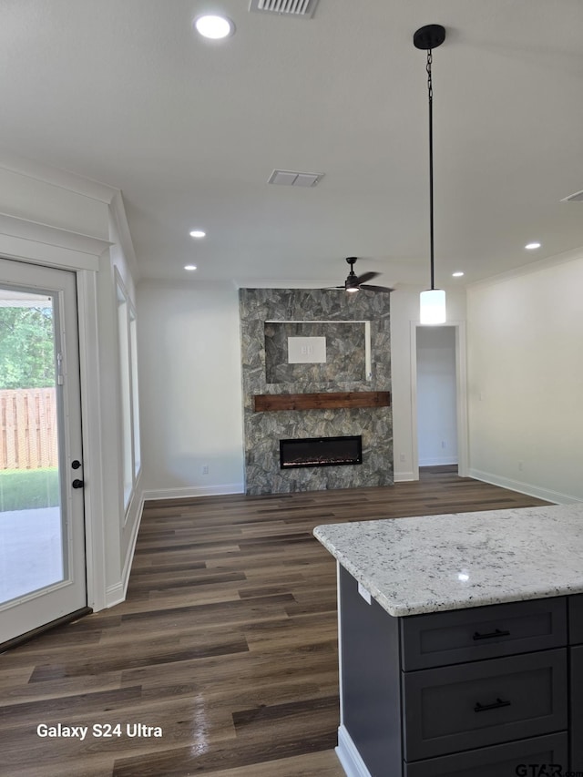 kitchen featuring ceiling fan, visible vents, dark wood-type flooring, and a fireplace