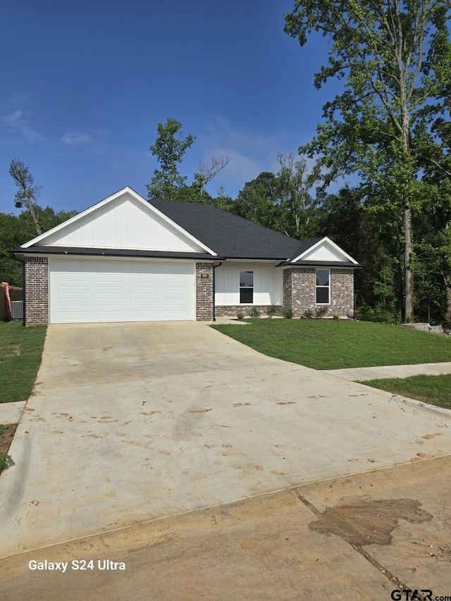 ranch-style house featuring board and batten siding, brick siding, a front lawn, concrete driveway, and an attached garage