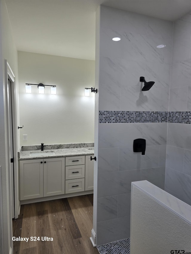 bathroom featuring a walk in shower, wood finished floors, and vanity