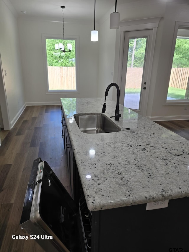 kitchen featuring a kitchen island with sink, baseboards, dark wood-type flooring, a sink, and decorative light fixtures