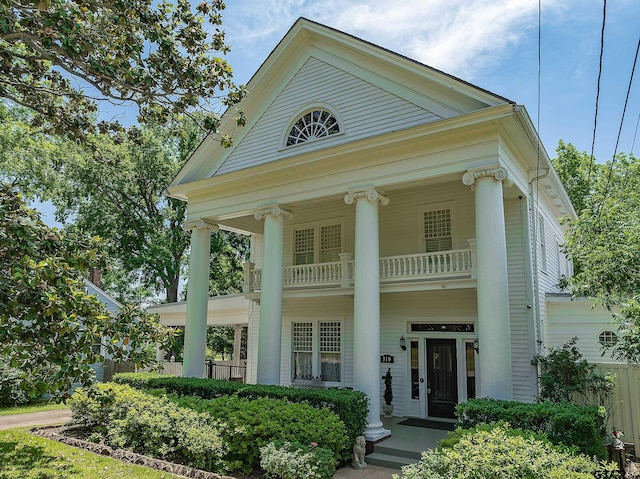 greek revival house featuring covered porch and a balcony