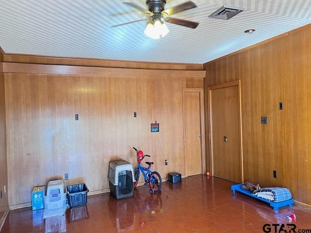 miscellaneous room featuring ceiling fan and wood walls