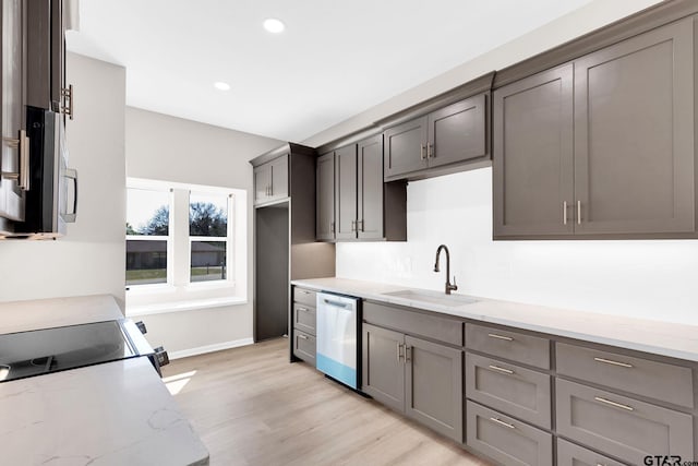 kitchen with light stone counters, sink, light hardwood / wood-style flooring, and appliances with stainless steel finishes