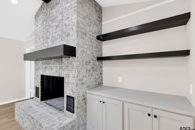 living room featuring a fireplace, light hardwood / wood-style floors, and lofted ceiling