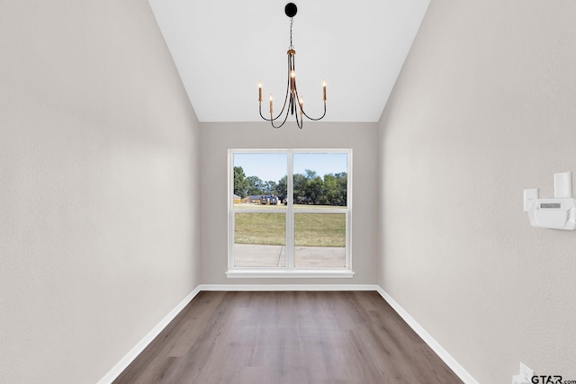 unfurnished dining area with a notable chandelier, lofted ceiling, and hardwood / wood-style flooring