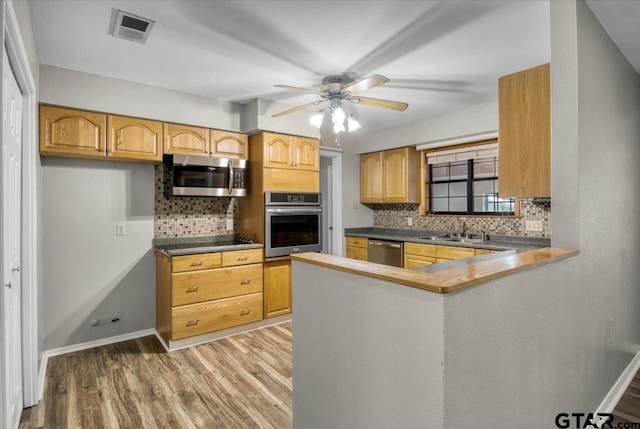 303 Westwood Dr, Troup, TX 75789 - kitchen with stainless steel appliances, backsplash, a sink, light wood finished floors, and ceiling fan