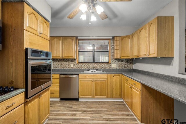 303 Westwood Dr, Troup, TX 75789 - kitchen featuring stainless steel appliances, a sink, a ceiling fan, light wood finished floors, and dark countertops