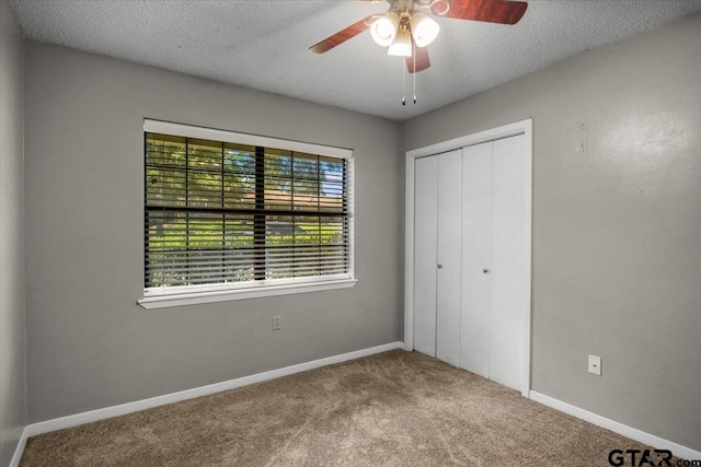 303 Westwood Dr, Troup, TX 75789 - unfurnished bedroom featuring carpet floors, a textured ceiling, a closet, baseboards, and a ceiling fan