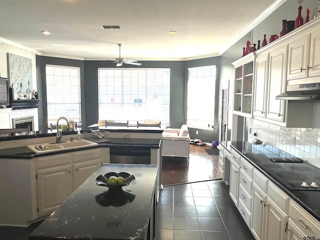 kitchen with ceiling fan, sink, crown molding, an island with sink, and dark tile patterned flooring