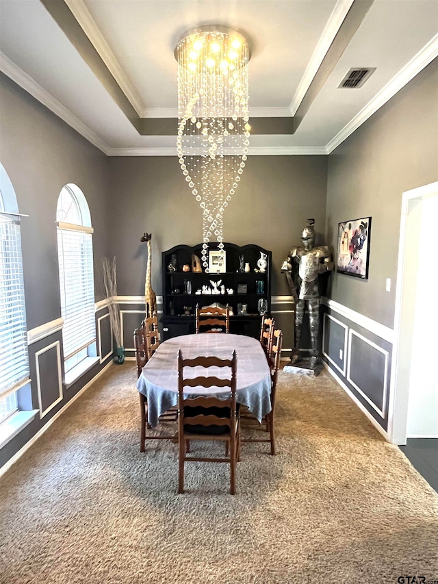 carpeted dining room with a chandelier, a tray ceiling, and ornamental molding