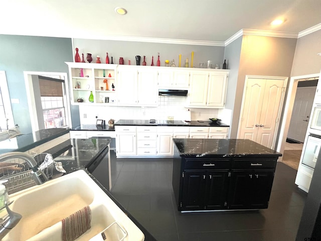 kitchen featuring white cabinets, backsplash, a kitchen island, and sink