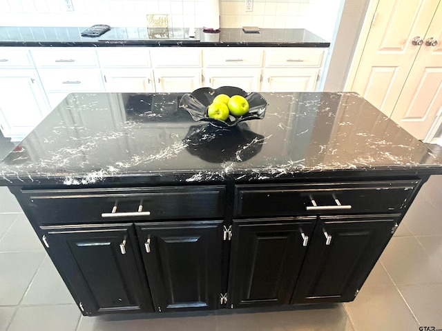 details featuring backsplash, dark stone countertops, and white cabinetry