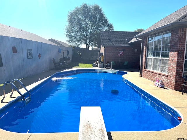 view of swimming pool with a diving board