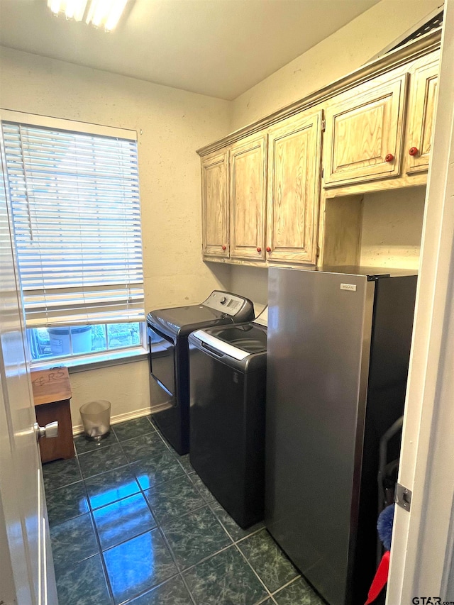 laundry room featuring cabinets, dark tile patterned floors, a wealth of natural light, and washer and dryer