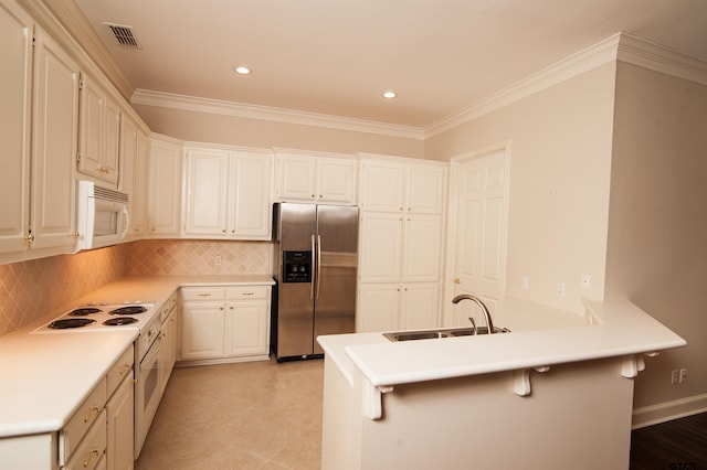 kitchen featuring white appliances, decorative backsplash, white cabinetry, kitchen peninsula, and a breakfast bar area