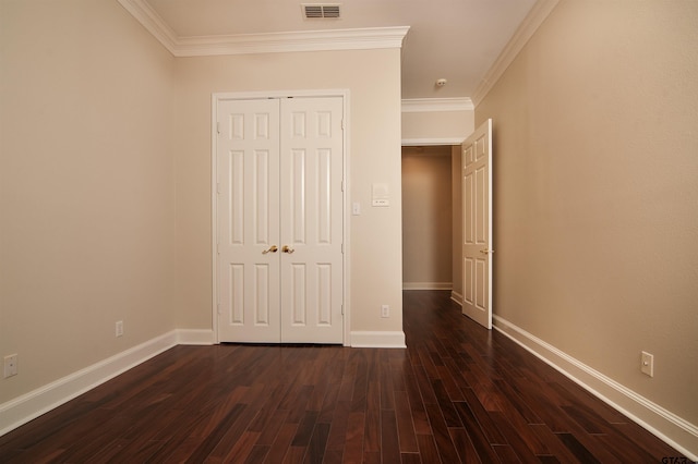 unfurnished bedroom with dark hardwood / wood-style flooring, crown molding, and a closet