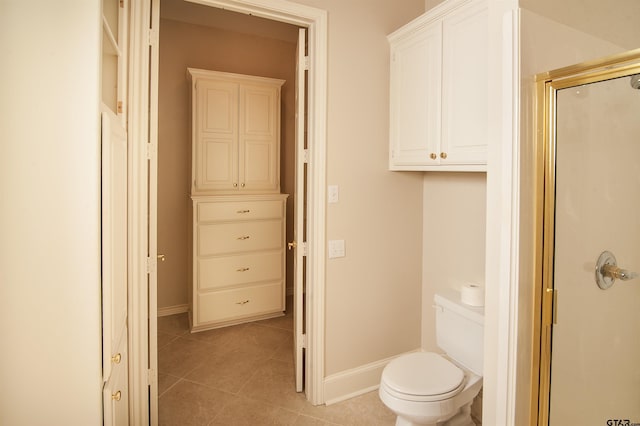 bathroom with tile patterned floors, toilet, and a shower with shower door