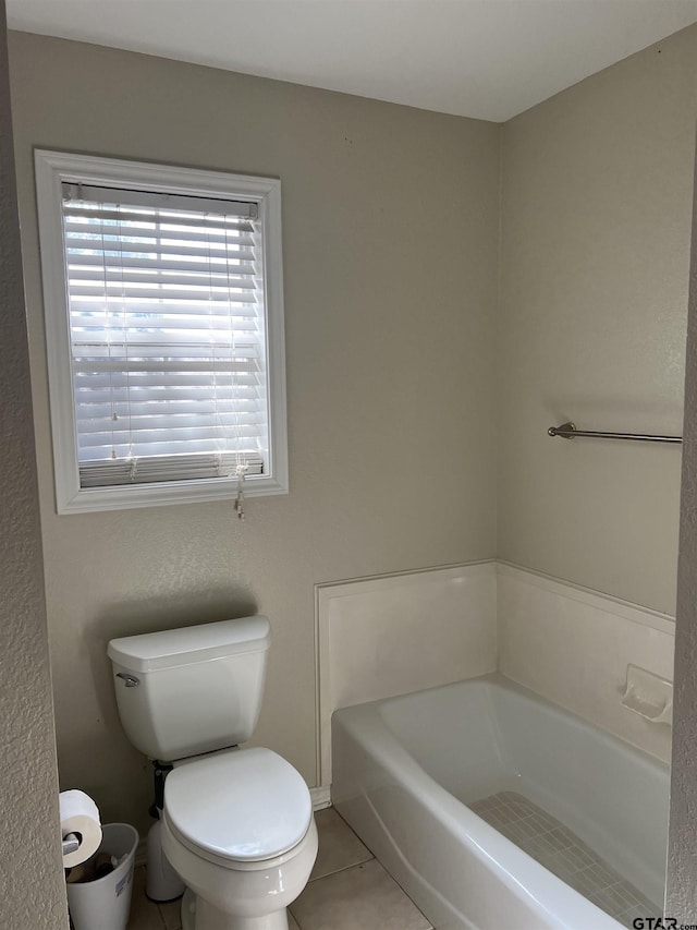 bathroom featuring tile patterned floors, a tub to relax in, and toilet