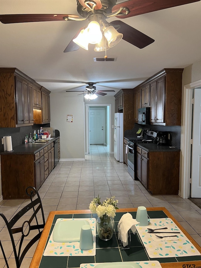 kitchen with light tile patterned floors, sink, dark brown cabinets, tasteful backsplash, and black appliances