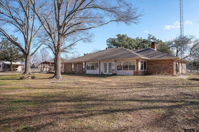 back of property featuring french doors and a lawn