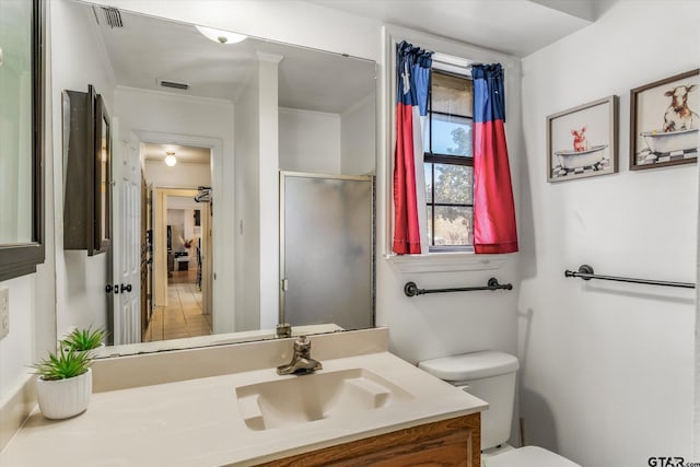 bathroom featuring vanity, toilet, and a shower with shower door