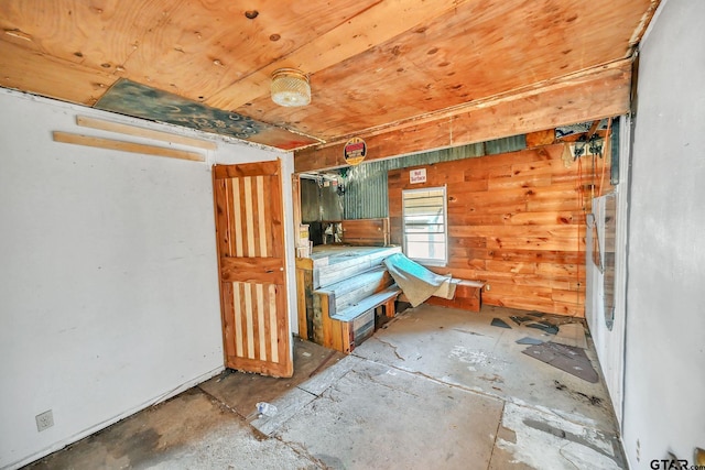 unfurnished bedroom with a garage, wooden ceiling, and wood walls