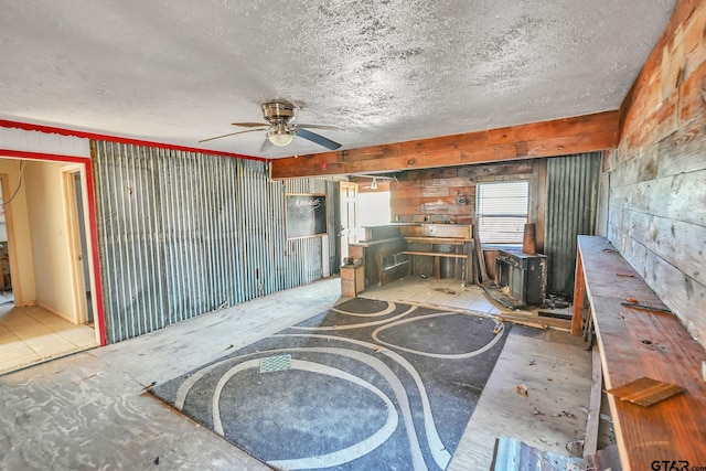 unfurnished living room featuring ceiling fan, wood walls, and a textured ceiling