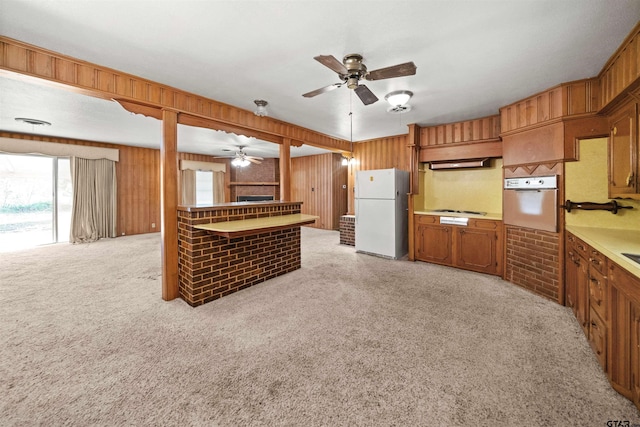 kitchen with light colored carpet, white appliances, hanging light fixtures, and brick wall