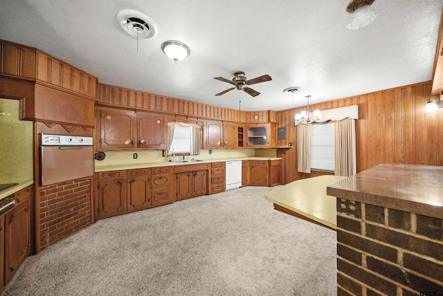 kitchen featuring pendant lighting, white dishwasher, wall oven, light colored carpet, and brick wall