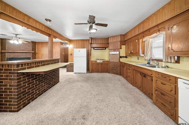 kitchen with brick wall, white appliances, sink, and light carpet