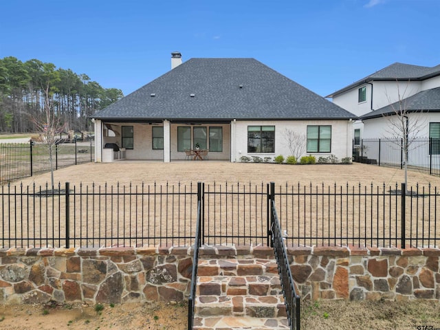 exterior space with a shingled roof, a patio area, and a fenced backyard